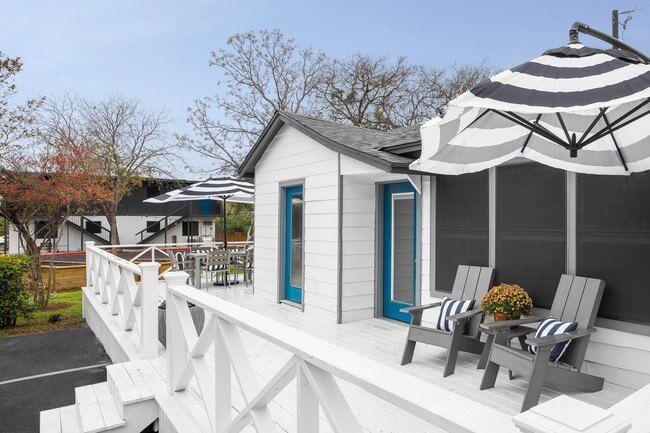 A white house with a striped umbrella on the porch.